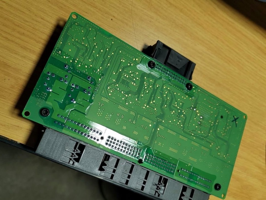 BMW footwell module (FRM) opened on the bench for repair, circuit board and connector block visible